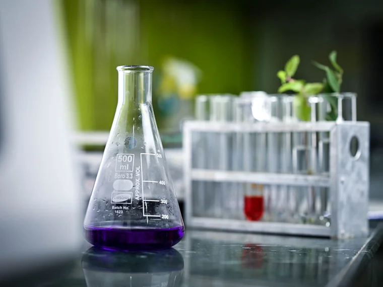 Matraz de 500 ml con una formulación en proceso junto a una gradilla de tubos de ensayo en el laboratorio